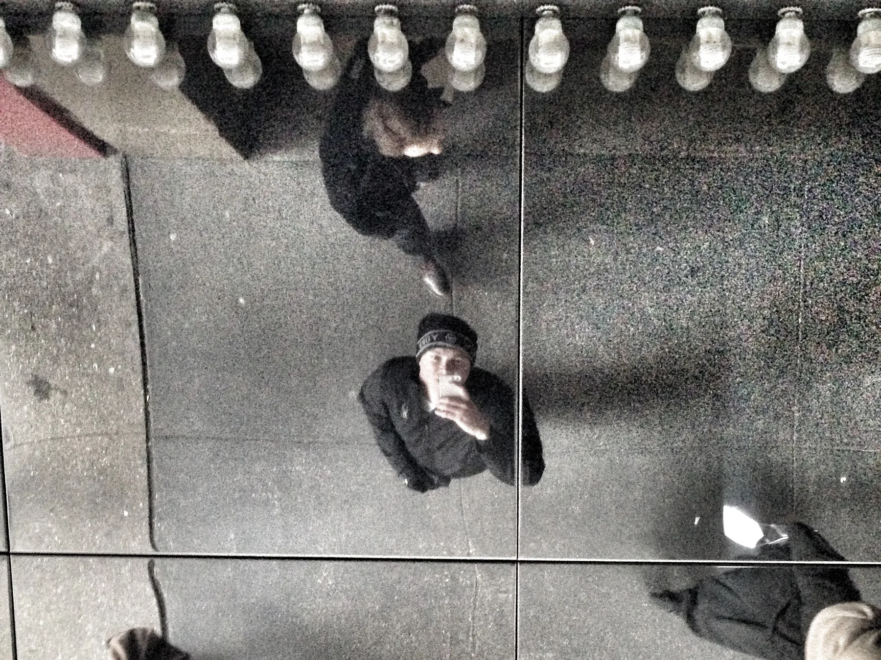 Selfie in a mirrored ceiling under marquee lights in New York.