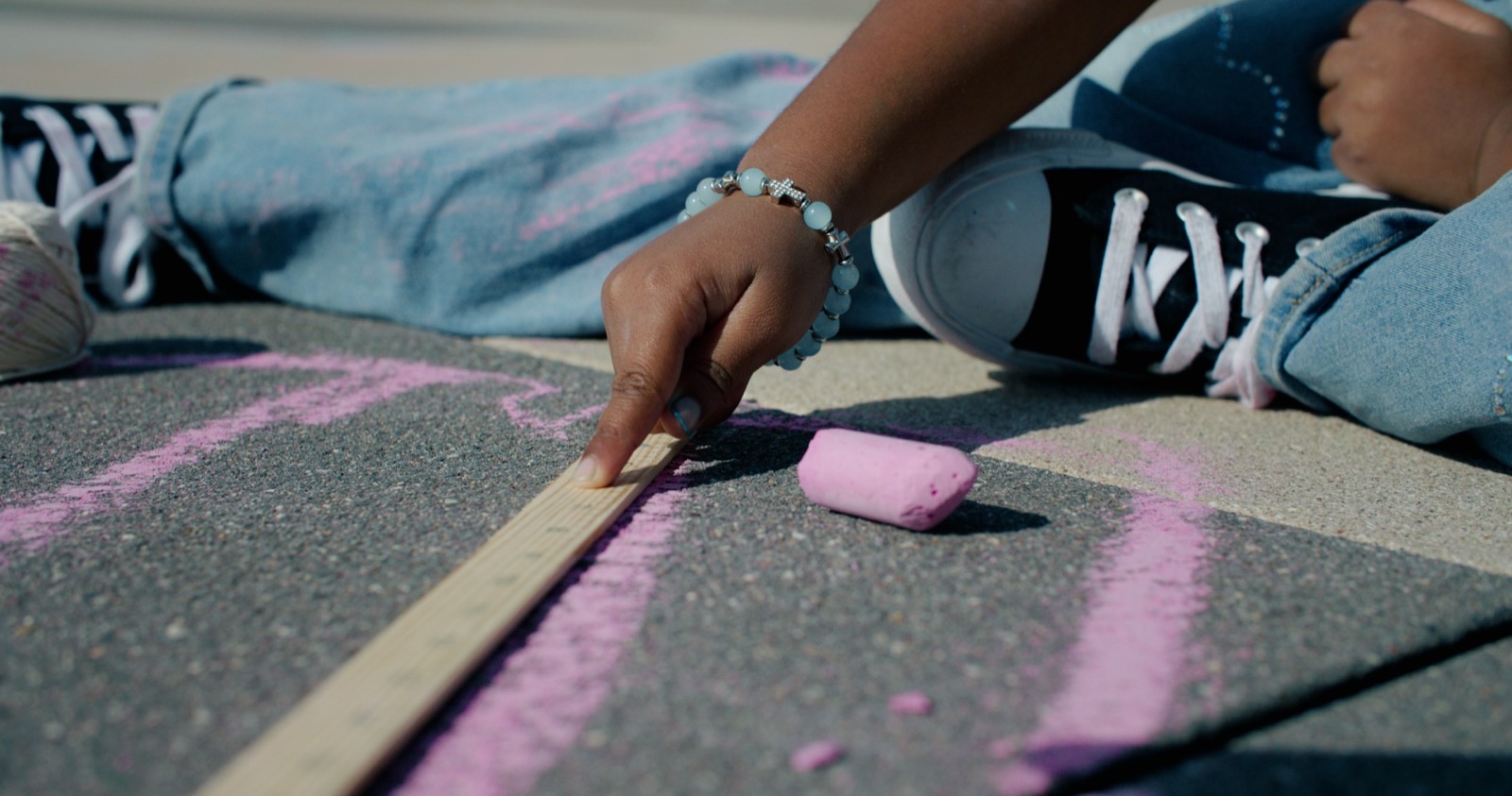 A student makes chalk art on the ground