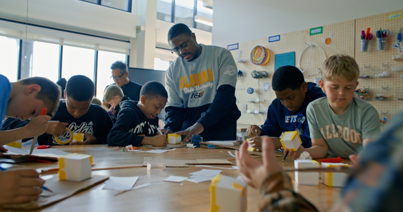 Students and an adult collaborate at a maker table